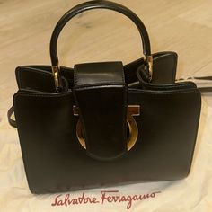 Small Black Ferragamo Handbag Multiple Compartments. Gold Hardware. Classic Ferragamo Logo On Front Strap. Top Handle And Detachable Crossbody Strap. Salvatore Ferragamo Bags, Ferragamo Handbags, Gold Handbags, Bags Black, Strap Top, Crossbody Strap, Salvatore Ferragamo, Gold Hardware, Top Handle