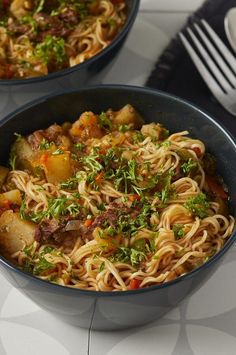 two bowls filled with noodles and vegetables on top of a table