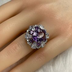 Details: Materials: Amethyst Gemstone, White Zircons, S925 Sterling Silver Plated with 18K White Gold Shape: Oval Size: Adjustable and fitable for all Descriptions: This oval shape design ring has one 12x10mm and six 3.5x3.5mm amethysts. The ring is made out of S925 sterling silver plated with 18K white gold. Surrounding the amethysts are twenty-four (24) white zircons, which make the amethysts stand out and shine. The arrangement of the amethysts makes it look like a flower shape from a distanc Formal Cubic Zirconia Rings With Stones, Formal Rings With Cubic Zirconia Stones, Elegant Multi-stone Amethyst Ring Gift, Elegant Cluster Ring With Stones As Gift, Luxury Purple Rings For Party, Luxury Purple Party Rings, Luxury Cubic Zirconia Rings With Stones, Adjustable Formal Crystal Ring With Gemstone, Adjustable Gemstone Crystal Ring For Formal Occasions