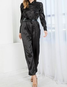 Introducing our gorgeous black satin jumpsuit that features a stylish front button closure and an elastic waistband with a matching belt. The V-neckline and cuffs at the wrist add a touch of elegance to the design. The fabric is made of 97% polyester and 3% spandex, offering a comfortable and lightweight feel. The model is wearing a small size, and the jumpsuit is not stretchy, so we recommend purchasing your regular size. The jumpsuit length is 57 inches, with a bust measurement of 36 inches an Black Satin Jumpsuit, Sequin Pant, Bow Crop Tops, Cream Crop Top, Belted Jumpsuit, Satin Jumpsuit, Asymmetric Jacket, Belt Jumpsuit, Cotton Coat