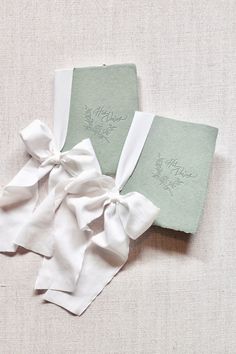 two wedding guest book covers with bows on the front and back, sitting on top of each other