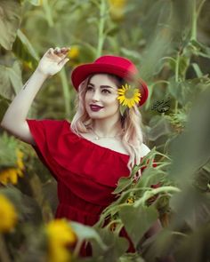 a woman in a red dress and hat poses for a photo with sunflowers