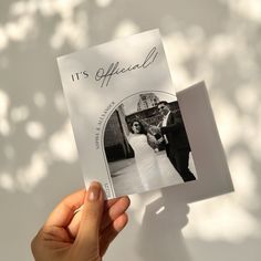 a person holding up a wedding card with the word it's offical