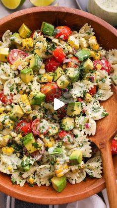 a wooden bowl filled with pasta salad on top of a table