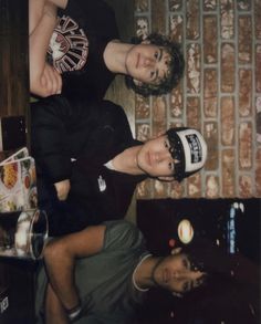 two young men standing next to each other in front of a brick wall and floor