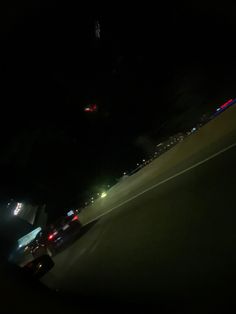 cars driving on the road at night time with lights from headlights in the dark behind them