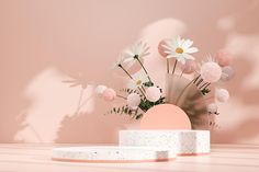 a vase filled with flowers sitting on top of a table next to a pink wall