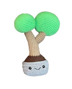 a crocheted toy with two green balls on it's head and eyes