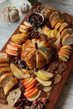 an assortment of breads, apples and cranberries on a wooden platter