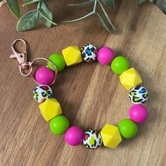 a close up of a bracelet on a table with a keychain and potted plant in the background