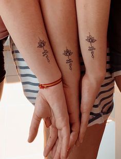 two people holding hands with tattoos on their arms