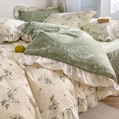 an unmade bed with green and white comforter on top of it in front of a window