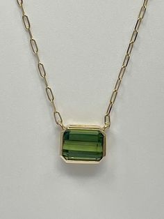 Add a touch of elegance to your jewelry collection with this stunning necklace from JewelsOfNewYork. The pendant features an emerald cut 3.98ct green tourmaline, set in 14kt yellow gold. The necklace is perfect for any occasion and will complement any outfit. The green color of the stone is breathtaking and will surely catch the attention of anyone who sees it. This necklace is a fine piece of jewelry, crafted with attention to detail. The pendant is designed in a classic style and is perfect for anyone who loves jewelry. The necklace is ideal for gifting and will make a great addition to any collection. Luxury Gold Emerald-cut Solitaire Necklace, Yellow Gold Emerald-cut Necklace With Bezel Setting, Emerald Cut Gemstone Emerald Necklace, Fine Jewelry, Luxury Emerald-cut Yellow Gold Necklace, Luxury Tourmaline Emerald Necklace, Tourmaline Necklace, Stunning Necklace, Green Tourmaline, Emerald Cut