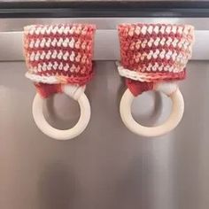 two rings are attached to the handle of a dishwasher, with red and white knitted material on them