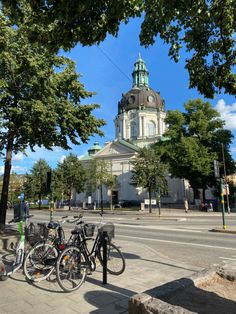 two bicycles parked in front of a building with a dome on top and trees lining the street