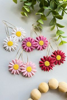 four different colored flowers are hanging from wooden beads