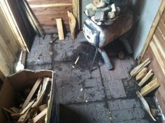 a pile of wood sitting on top of a brick floor next to a stove and door