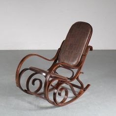 a wooden rocking chair sitting on top of a gray floor