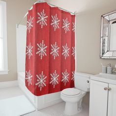 a red shower curtain with white snowflakes on it in a bathroom next to a toilet