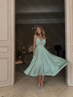 a woman standing in an open doorway wearing a green dress