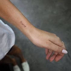 a person with a small tattoo on their left wrist holding the hand of another person