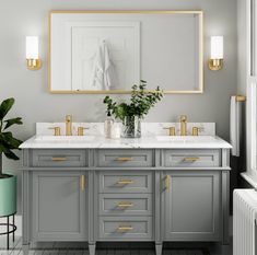 a bathroom vanity with two sinks and gold trim on the mirror above it is also a plant