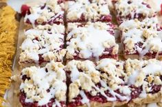 raspberry crumble bars with white icing on a cutting board