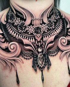 a woman's chest is covered in tattoos and jewelry, including an elaborate necklace