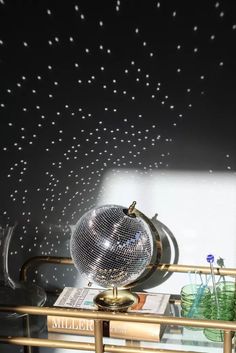 a disco ball sitting on top of a glass shelf next to a wall with stars painted on it