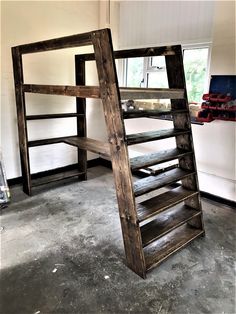 a wooden ladder sitting on top of a cement floor next to a white wall and window