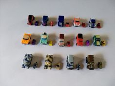 a group of toy cars sitting next to each other on a white surface with one car in the middle