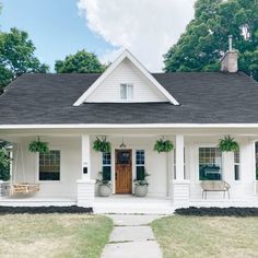 a white house with two porches and plants on the front door is shown in this image