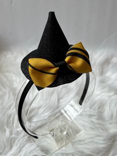 This little witch hat fascinator is perfect for Halloween or any day of the year, and can be worn by all ages! Witch hat is made of glitter foam and is adorned with a cute little gold and black striped bow that is approximately 2.75 inches in width.  Hat is approximately 3.5 inches tall, and 4- inches wide. Witch hat can be attached to your choice of 2-inch alligator clip, stretchable nylon baby headband or plastic headband. Plastic headband is soft and flexible, which makes for a comfortable fi Gold Costume Hats And Headpieces For Halloween, Halloween Costume Hat Accessories, Halloween Cat Ears Hair Accessories For Costume Party, Halloween Costume Party Cat Ears Hair Accessories, Spooky Black Costume Hats And Headpieces For Party, Halloween Cat Ears Costume Accessories, Gold Halloween Party Costume Headpiece, Adjustable Cat Ears Costume Hat For Halloween, Adjustable Cat Ears Headpiece For Halloween