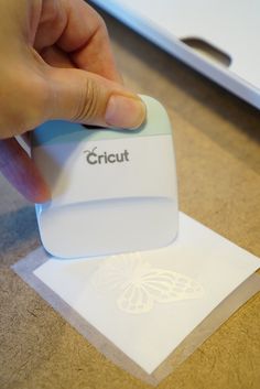 a hand is pressing the button on a small device that's sitting on top of a piece of paper