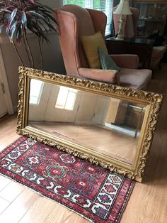 a large mirror sitting on top of a wooden floor next to a chair and rug