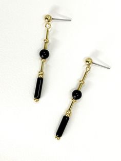 These long, dangle earrings feature polished onyx stone.  The geometric cut of the stone and brass elements creates a modern and minimalistic design while the variation in shapes adds detail and interest. The deep black of the onyx stone and the warm, metallic tone of the brass highlights the materials and creates contrast.  The earrings are finished with brass ball stud with stainless steel earring post.  Onyx is a semi precious gemstone known for its striking black color and smooth, glossy app Minimalist Black Linear Drop Earrings, Minimalist Black Drop Earrings, Minimalist Black Linear Earrings For Gifts, Minimalist Black Linear Earrings As Gift, Modern Onyx Drop Earrings, Minimalist Black Long Drop Earrings, Modern Black Long Drop Jewelry, Modern Gold Onyx Earrings, 1920s Jewellery