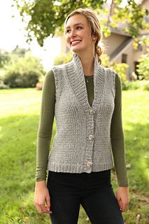 a woman standing in the grass wearing a vest