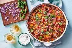 a large pot filled with food next to two glasses and a cutting board on the table