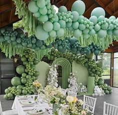 a dining room with green balloons hanging from the ceiling and tables set for an event