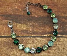 "Shades of opal, emerald green and peridot are displayed in this sparkling Swarovski cup chain bracelet. Each carefully hand set 8mm (39ss) crystal is held with four prongs in an antique silver 15 cup bracelet, closed with a lobster claw clasp. The pale green opals are complimented with peridot and emerald crystals, intermingled with chrysolite crystals that shimmer in pale green. These 39ss chatons are set in this nickle free metal, silver toned bracelet. A 2\" extender chain finished with an e Green Round Crystal Jewelry, Green Bracelets With Sparkling Stones For Gift, Green Bracelets With Sparkling Stones As Gift, Green Crystal Round Bracelets, Green Crystal Bracelets With Sparkling Stones, Green Faceted Crystal Bracelet For Jewelry Making, Elegant Green Faceted Crystal Bracelet, Green May Birthstone Bracelet, Green Faceted Bracelet