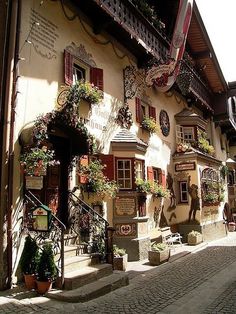 an old building with flowers growing on the windows and balconies in front of it