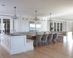 a large kitchen with white cabinets and an island in the middle is surrounded by gray chairs