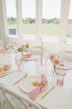 the table is set with plates and pink napkins