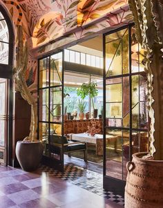 the lobby is decorated with an artistic mural and large potted plants in front of glass doors