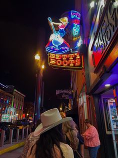 people are walking down the street in front of neon signs and buildings at night time