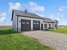 a large white house with two garages and a gravel road in front of it