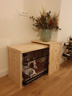 a wooden crate with a dog in it on top of a table next to a vase filled with flowers