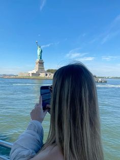 a woman taking a photo of the statue of liberty