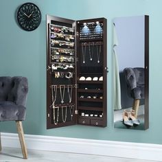 a mirror that is next to a wall with jewelry on it and a chair in front of it