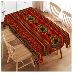 a red table cloth with an intricate design on it and two chairs in the background